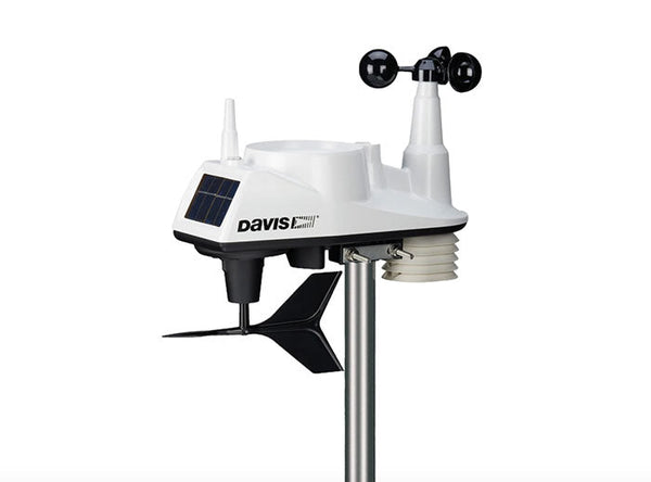 White wireless weather station by Davis Instruments with a solar panel and anemometer on a metal pole.
