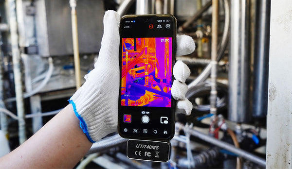 Smartphone thermal imaging camera, compatible with iOS and Android, by Uni-Trend, showing temperature readings in a piping system.
